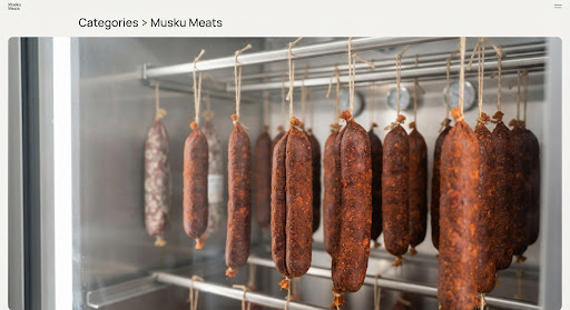 Hanging links of dry cured beef chorizo with smoky pimenton paprika coating inside an aging curing cabinet.